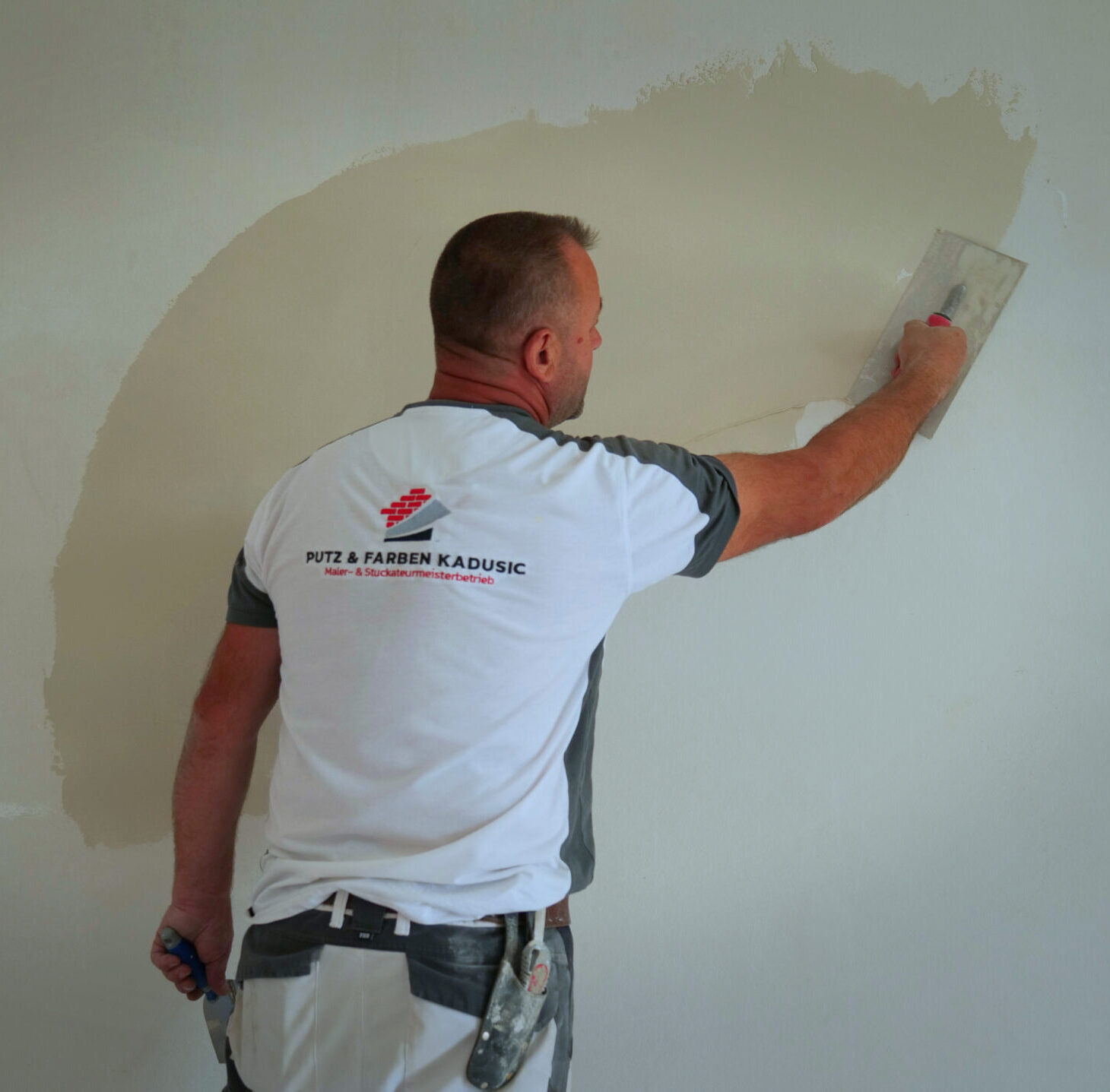 Ein Handwerker von Putz & Farben Kadusic bringt Putz sorgfältig auf eine Wand auf