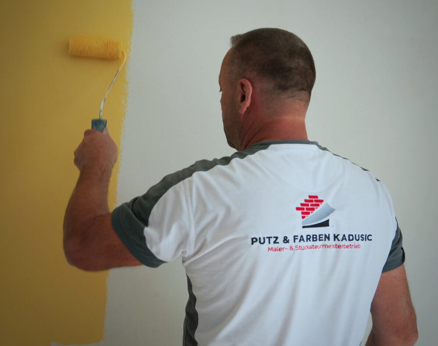 Handwerker beim Streichen einer Wand mit einer Farbrolle